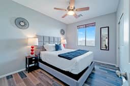 Bright modern bedroom with queen bed, ceiling fan, and chic flooring
