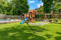 Family-friendly backyard with hammock, playset, and fenced pool
