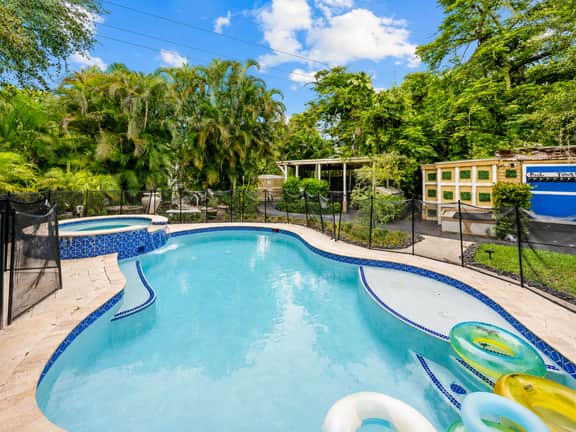Tropical resort-style pool with spa, float loungers, and lush private surroundings