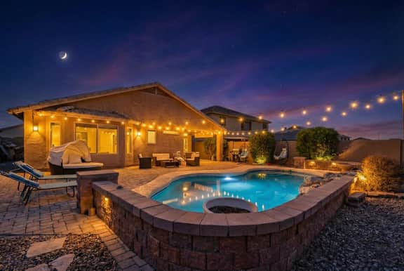 Twinkle-lit backyard oasis with pool, fire pit & cozy lounge seating