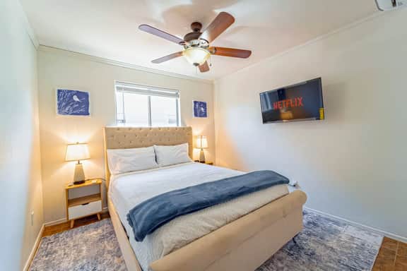 Bright, cozy bedroom with plush bed, ceiling fan and Netflix-ready TV