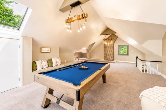 Bright loft game room with pool table, skylight, and cozy lounge seating