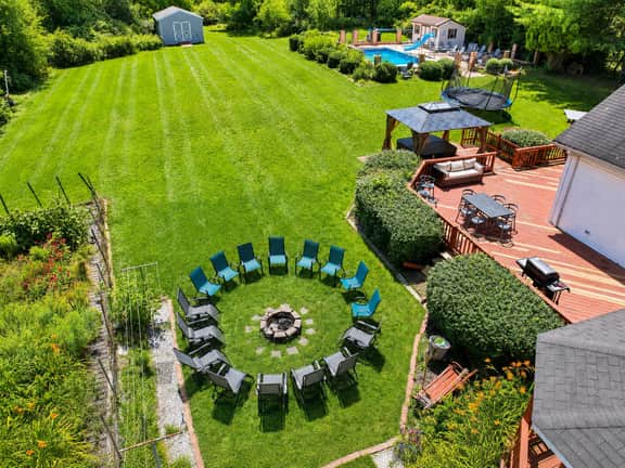 Sprawling backyard with fire pit, deck dining, and private pool retreat