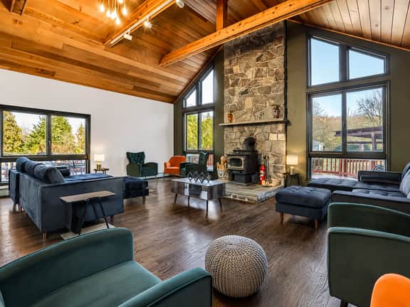 Vaulted-ceiling great room with stone fireplace and bright forest views