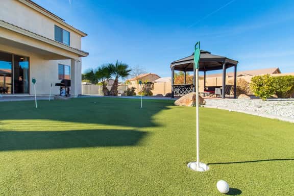 Spacious backyard with a putting green and open grassy area. Perfect for outdoor games, relaxation, and enjoying sunny days in a private setting.